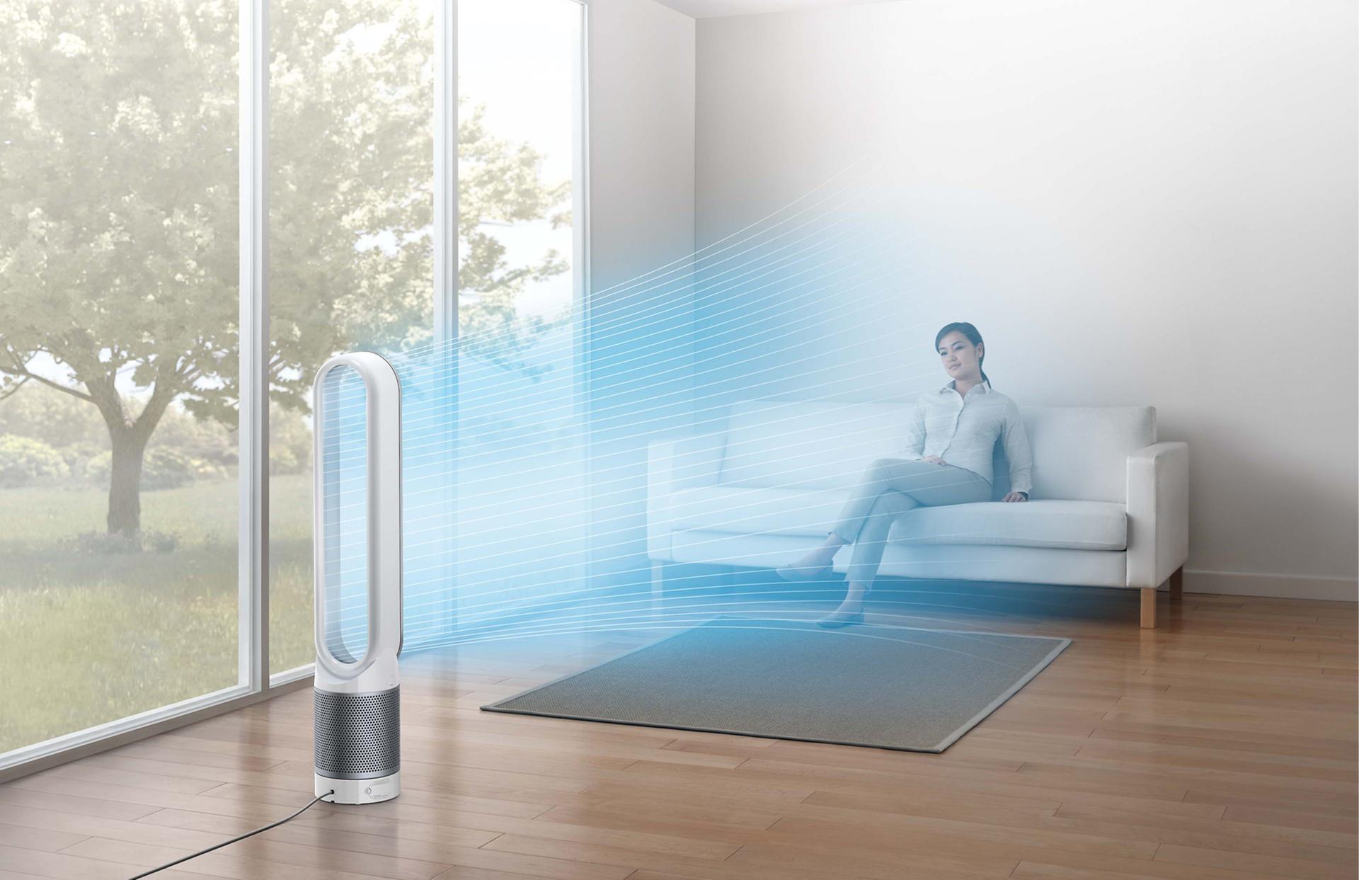 Woman sitting on sofa beside Dyson Pure Cool™ purifier fan