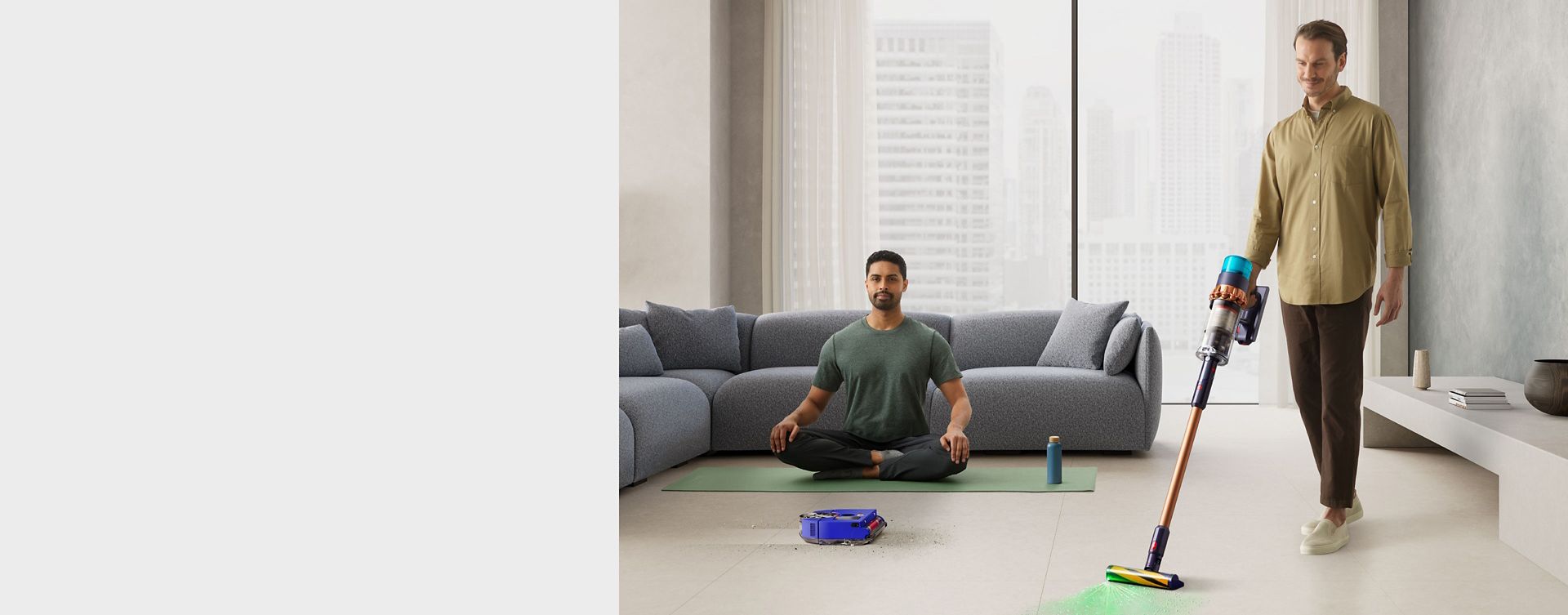 Man in a home using the Gen5detect Absolute vacuum cleaner while another man meditates while the Dyson 360 Vis Nav robot vacuum cleaner cleans a dirty floor