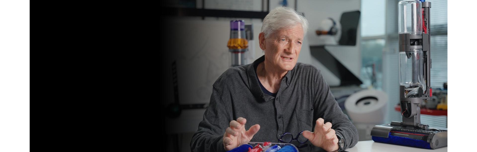 James Dyson sitting in his office, surrounded by Dyson products and parts.