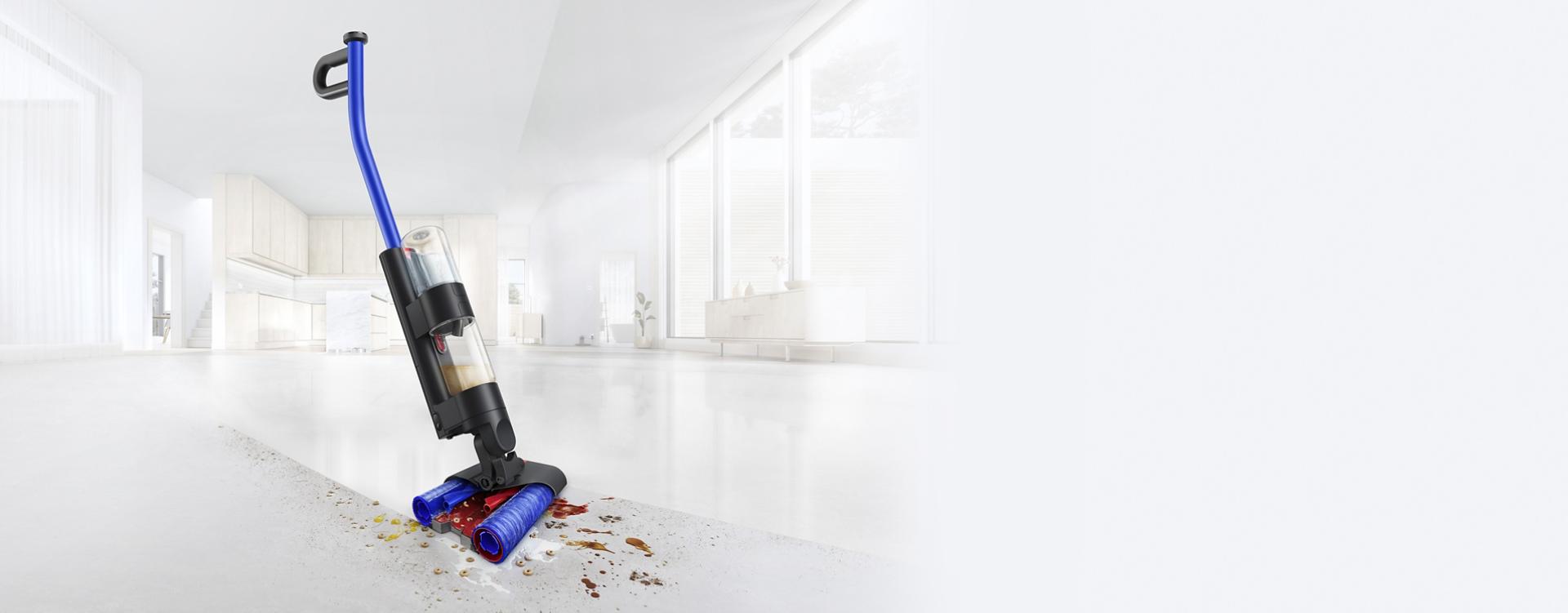 مكنسة التنظيف الرطب Dyson WashG1 بينما تقوم بإزالة آثار أقدام موحلة على أرضية صلبة.