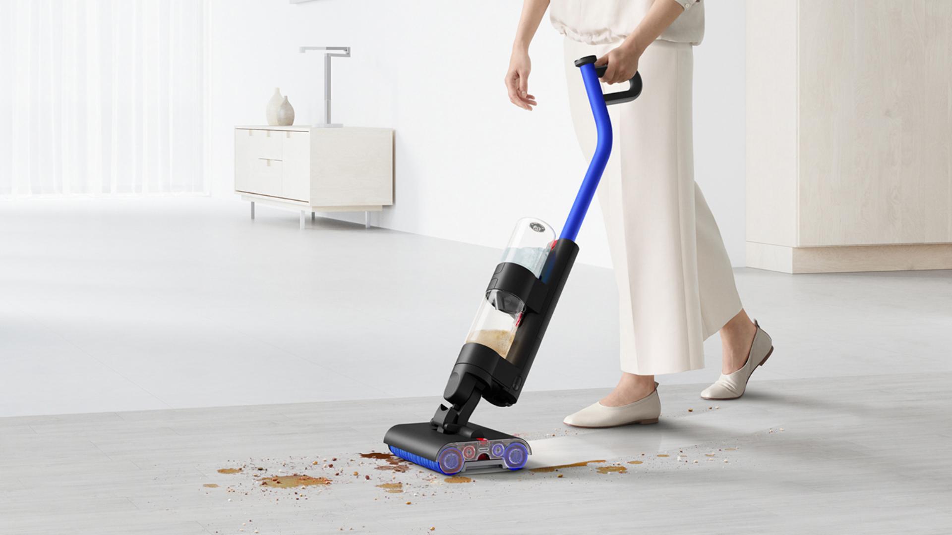مستخدم يُنظِّف المخلفات والانسكابات على أرضية صلبة باستخدام مكنسة التنظيف الرطب Dyson WashG1