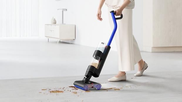 مستخدم يُنظِّف المخلفات والانسكابات على أرضية صلبة باستخدام مكنسة التنظيف الرطب Dyson WashG1