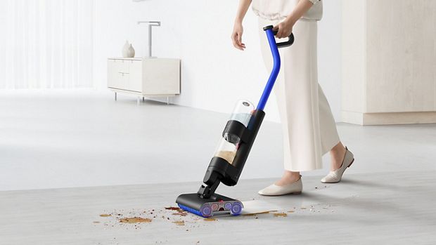 مستخدم يُنظِّف المخلفات والانسكابات على أرضية صلبة باستخدام مكنسة التنظيف الرطب Dyson WashG1