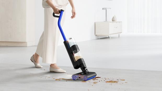 User cleaning debris and spills on a hard floor with a Dyson WashG1 wet cleaner