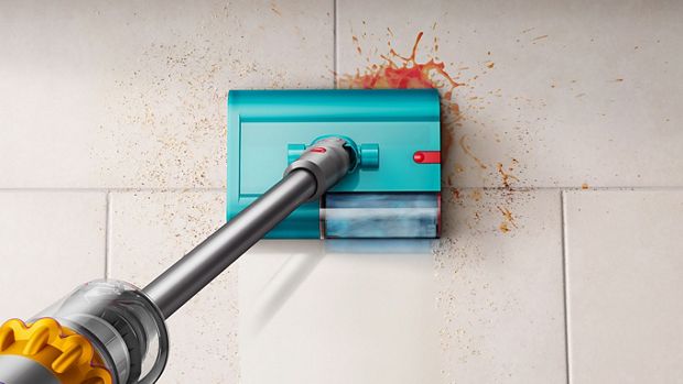 An aerial view of a Dyson wet and dry cleaner removing debris and spills on a tile floor