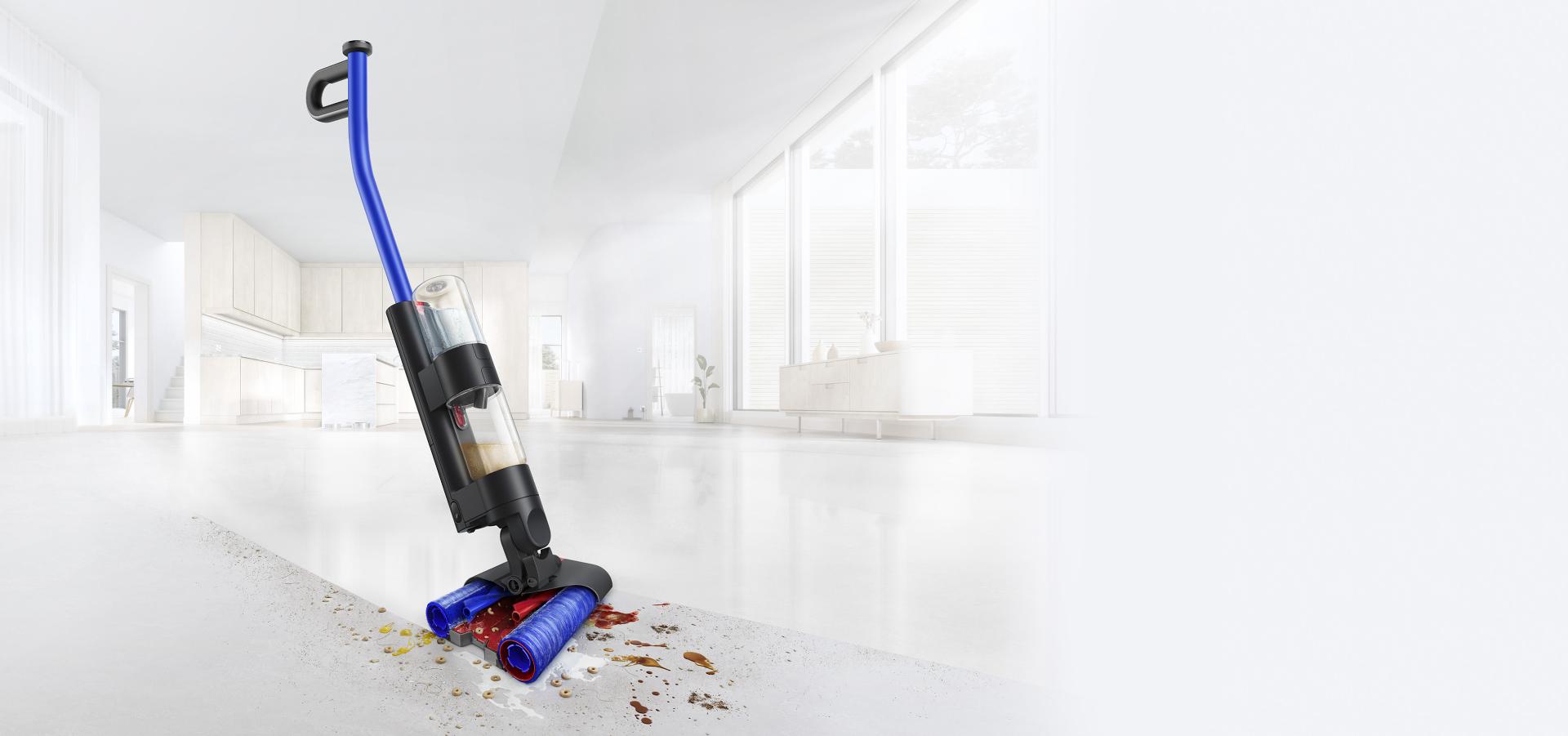 مكنسة Dyson WashG1 بينما تُنظِّف المخلفات والانسكابات على أرضية صلبة في غرفة معيشة