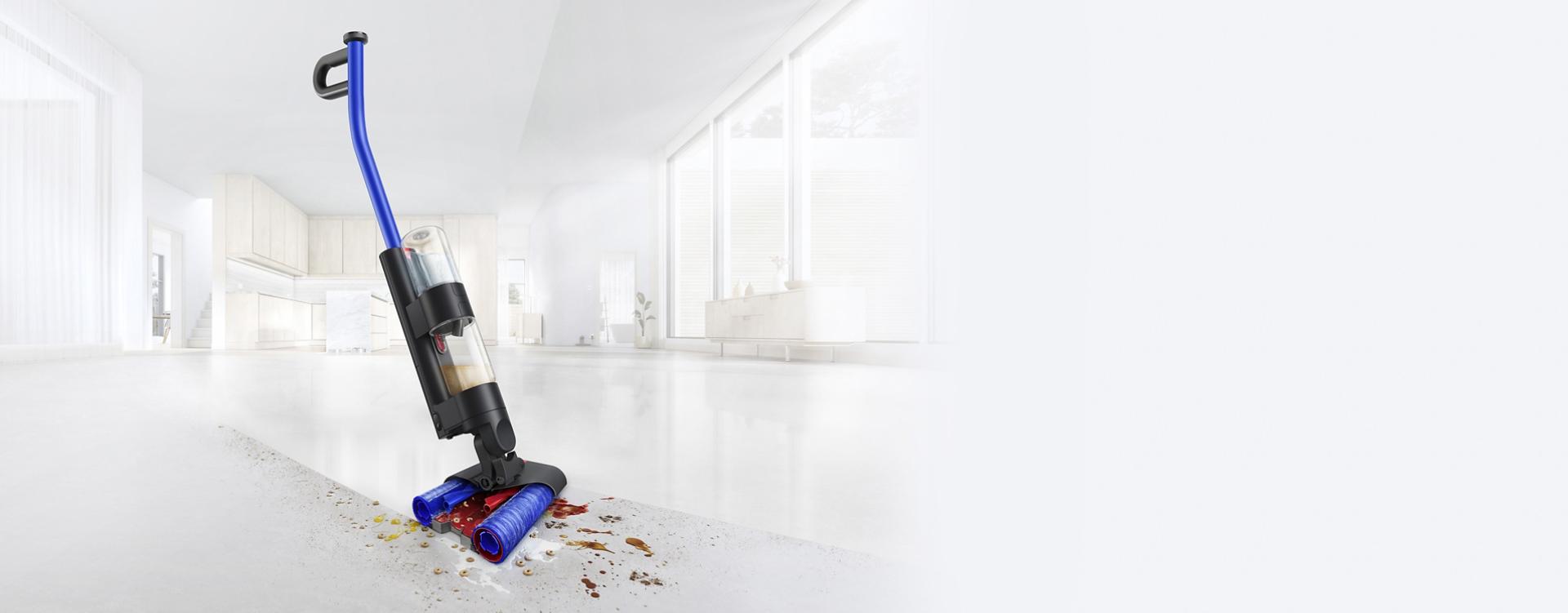 مكنسة Dyson WashG1 بينما تترك أثراً نظيفاً على أرضية مطبخ صلبة مليئة بالفوضى