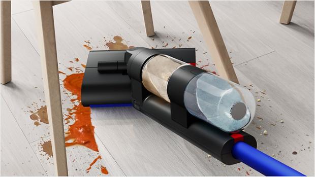 A user gliding the Dyson WashG1 wet cleaner to remove large food spills under a dining chair