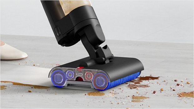 A user guiding the Dyson WashG1 wet cleaner over  wet and dry food spills on a hard kitchen floor