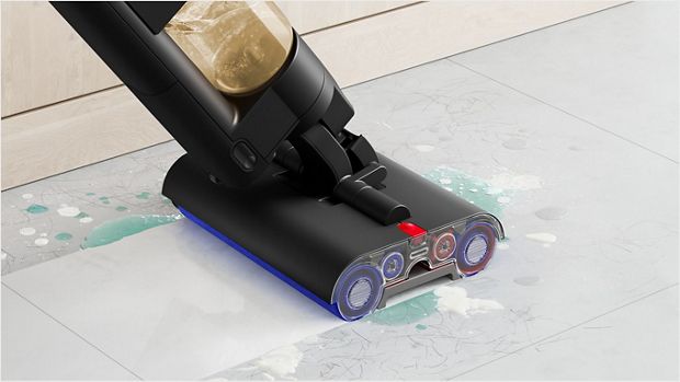 A close-up of the Dyson WashG1 wet cleaner tackling muddy pawprints on a hard floor