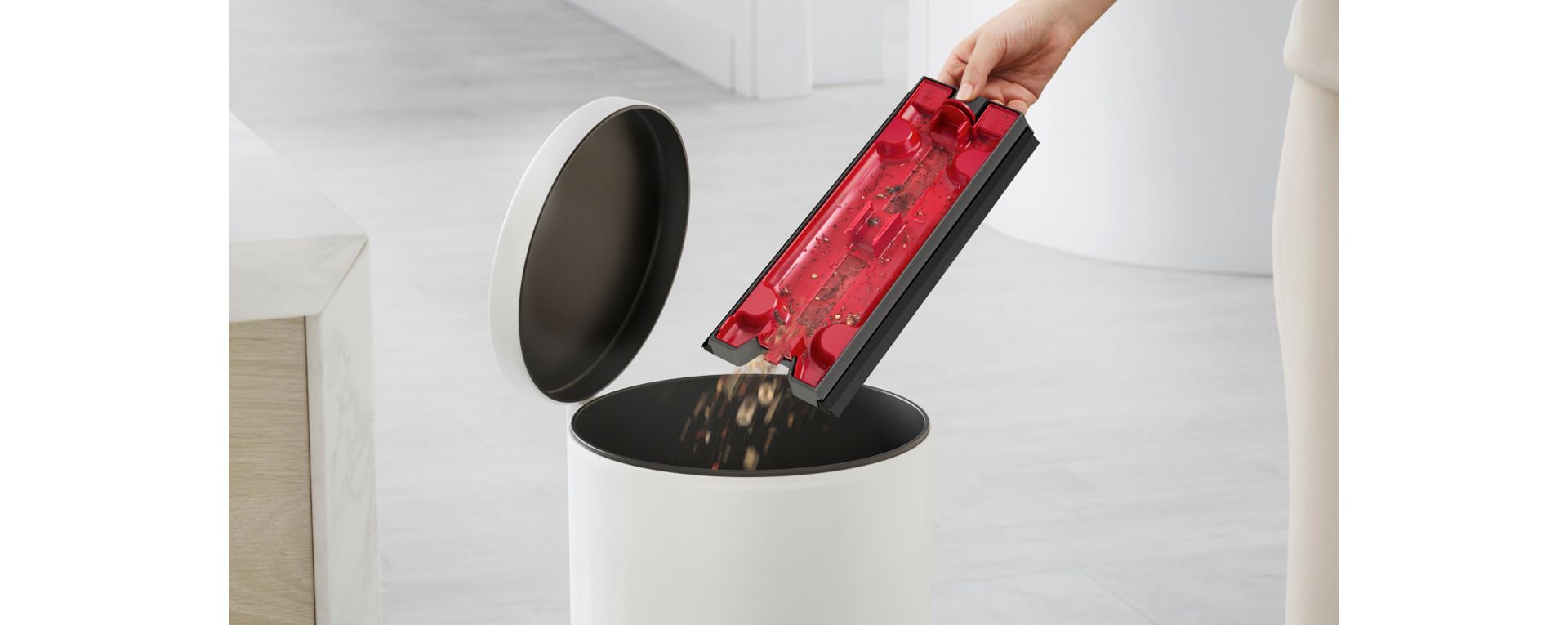 A user's hand emptying the debris into a bin