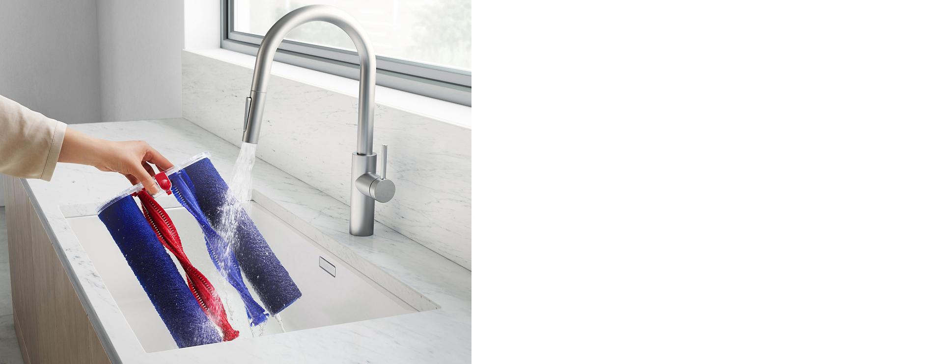 Naudotojas po tekančiu vandeniu skalauja mikropluošto volelius ir antrinių volelių šepečius.