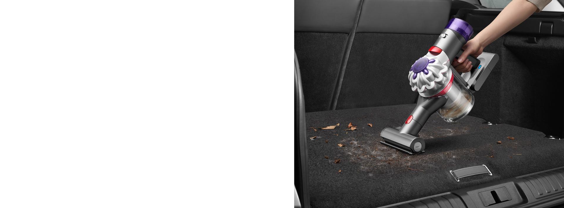 A Dyson Car+Boat handheld vacuum cleaner with the Mini motorised tool is used to deep clean the carpet in a car boot.