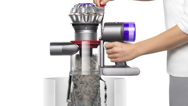 Osoba koja higijenski prazni svoj usisavač Dyson za automobil + čamac u kućni otpad.