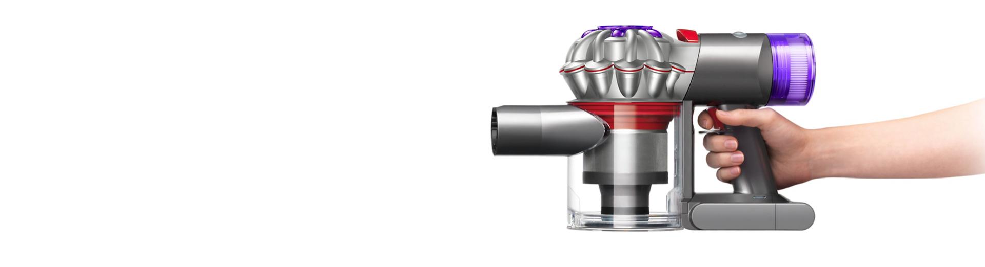 A hand holds the ergonomically designed handle of the Dyson Car+Boat vacuum.