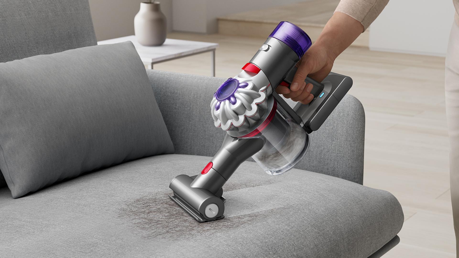 A Dyson Car+Boat vacuum cleaner is used with the Mini motorised head to deep clean sofa cushions.
