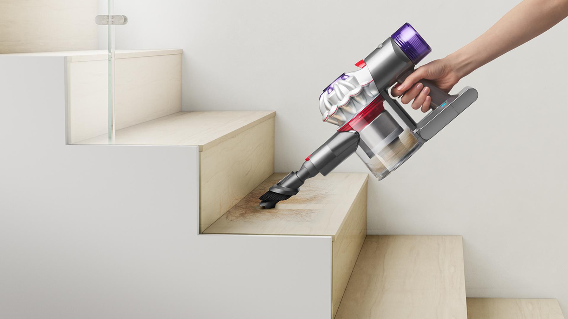 A Dyson Car+Boat vacuum cleaner is used with the Combination tool to clean and dust stairs.