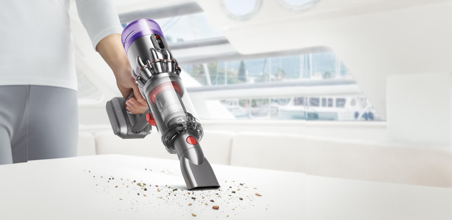 سيدة تُخرِج المكنسة المحمولة Dyson Humdinger من وحدة الإرساء الجدارية.