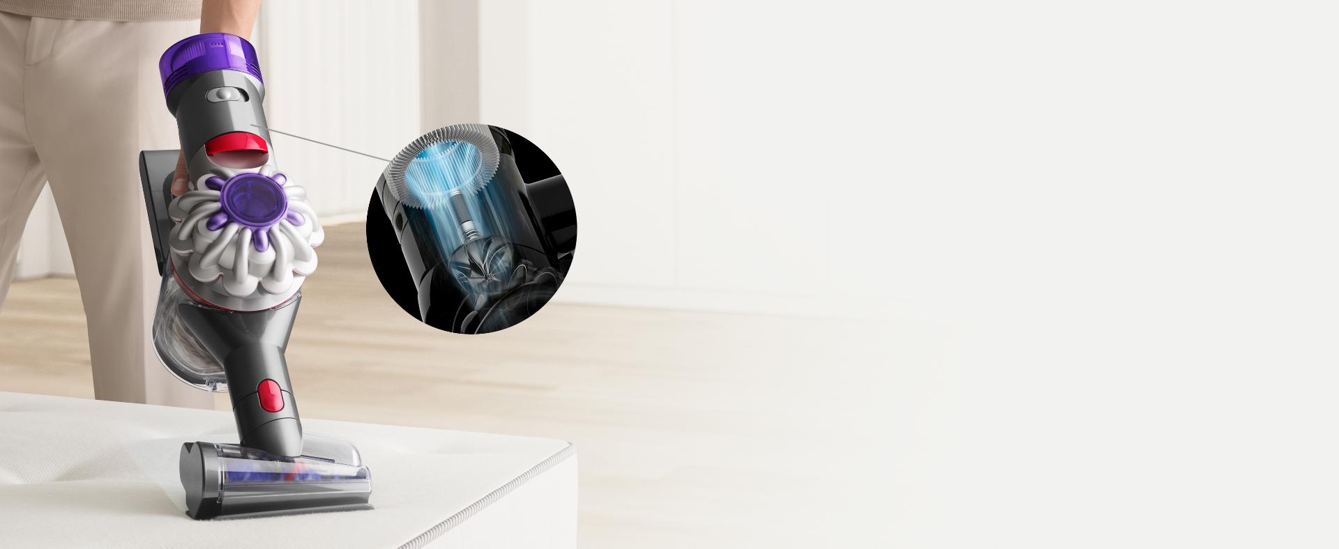 User cleaning a mattress with the Hair screw tool attachment. Inset illustration with blue airflow lines to simulate powerful suction.