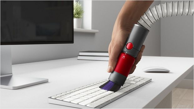 User cleaning a computer keyboard on a desk, with the Scratch-free dusting brush attachment.
