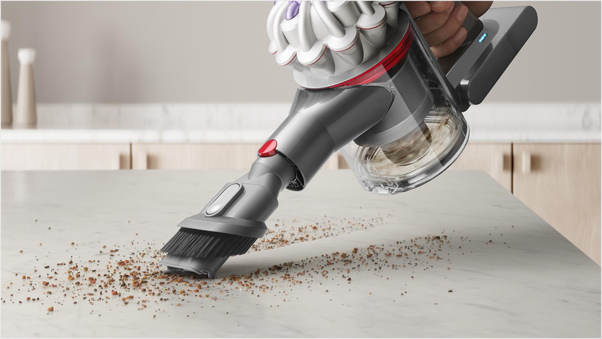 User cleaning crumbs from a kitchen countertop, with the Combination tool attachment.