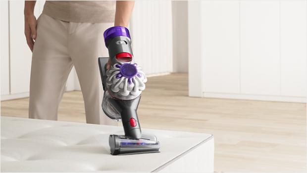 User cleaning a mattress with the Hair screw tool attachment.