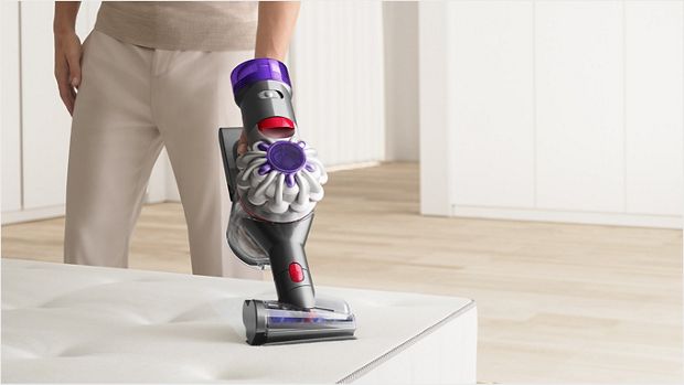 User cleaning a mattress with the Hair screw tool attachment.