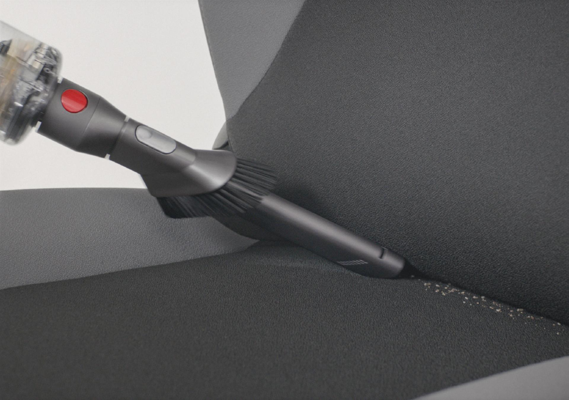 다이슨 옴니-글라이드™ 무선 청소기를 핸디 모드 전환해 자동차 시트를 청소하는 모습.