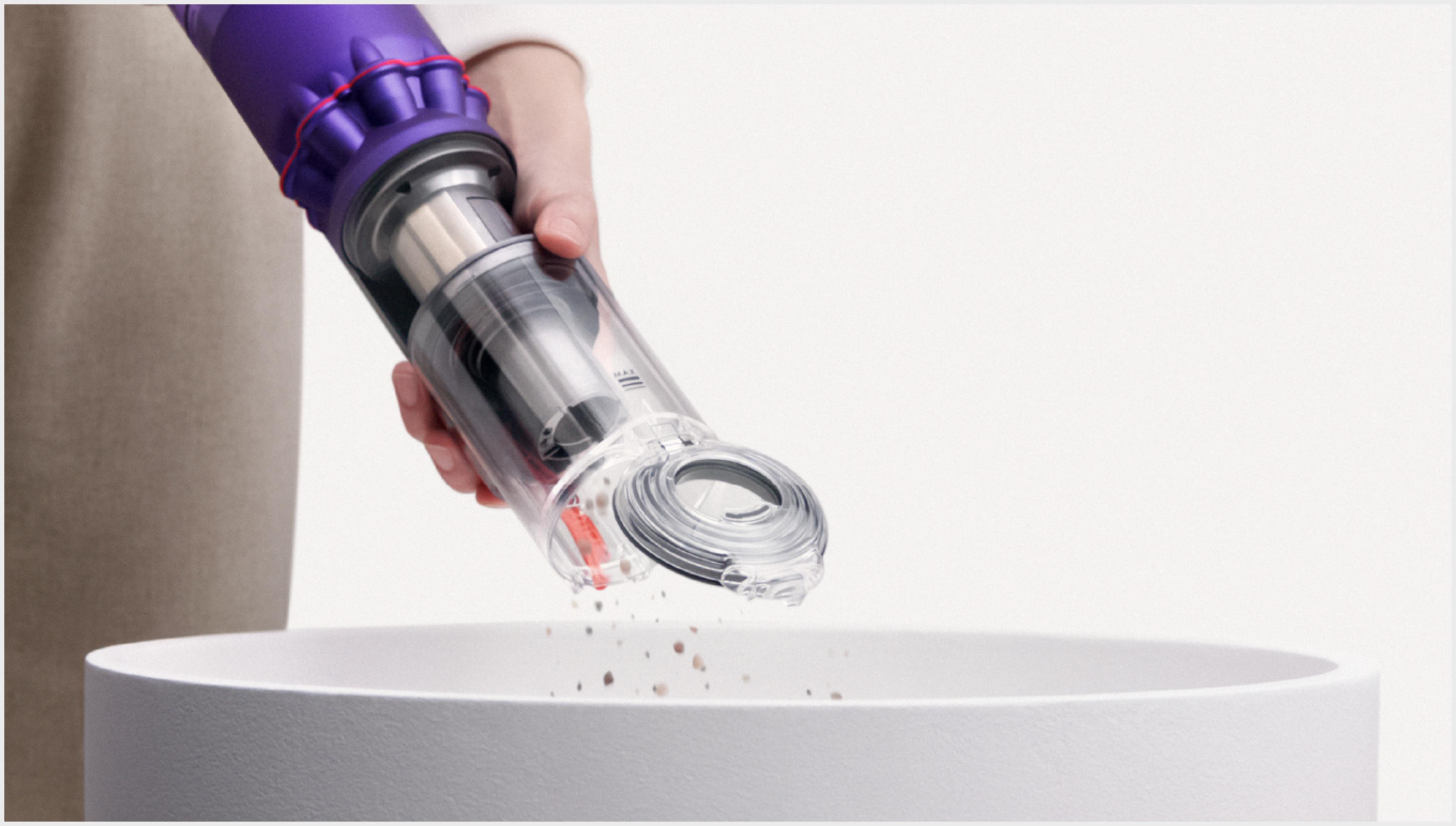 쓰레기통에 다이슨 옴니-글라이드™+ 무선 청소기의 먼지통 비우는 모습.