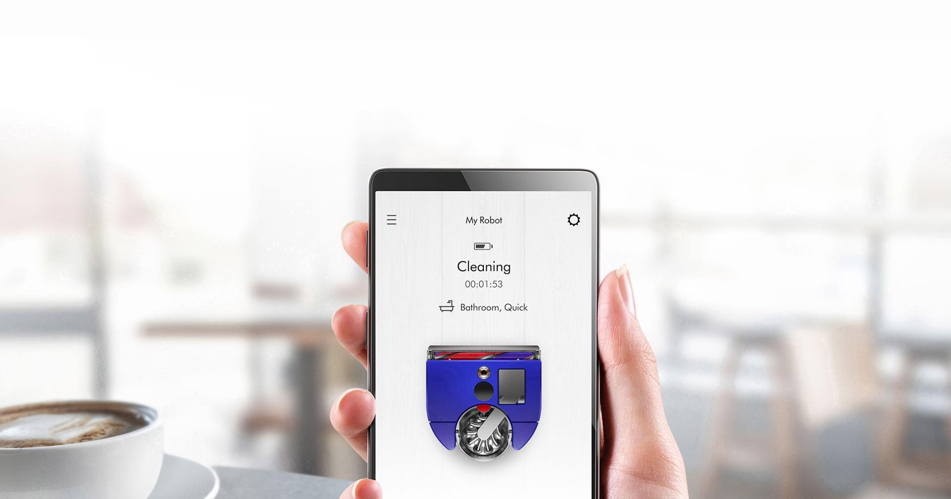 Close-up of MyDyson app on a smartphone, with a cafe scene in the background.