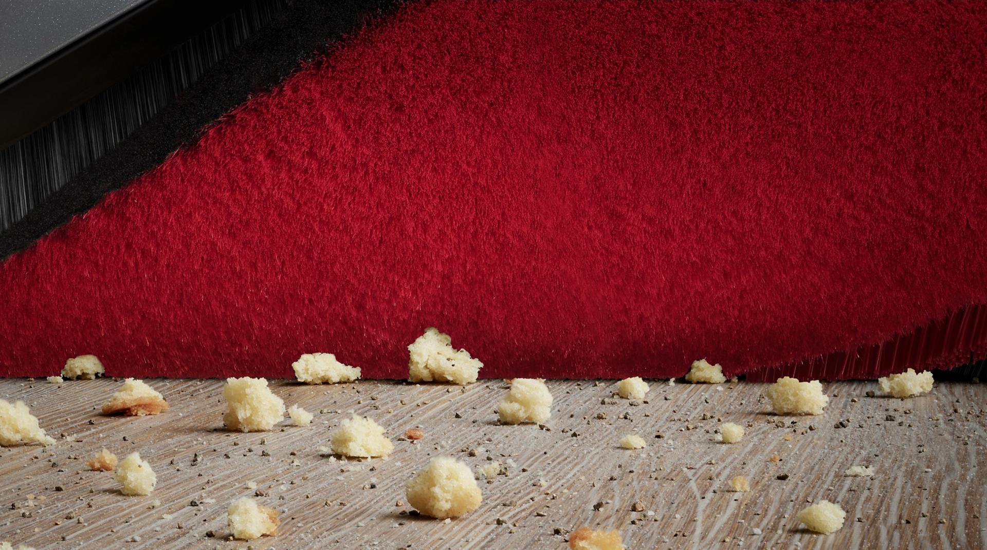 صورة مُقرَّبة للألياف المحاكة بمكنسة Dyson 360 Vis Nav بينما تلتقط المخلفات من أرضية صلبة