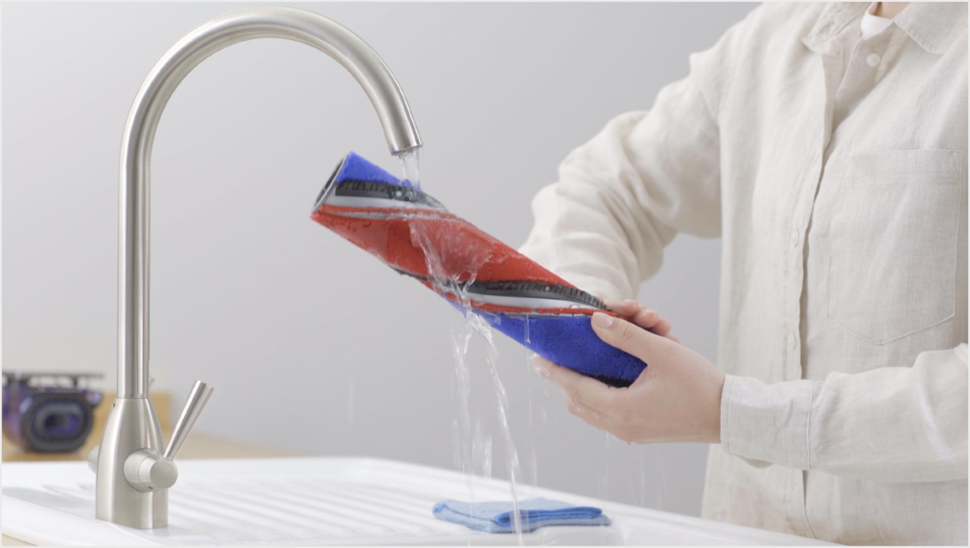 Person rinsing the washable brush bar under a tap