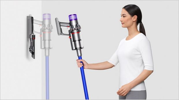 Woman placing Dyson V11™ vacuum into wall charging dock
