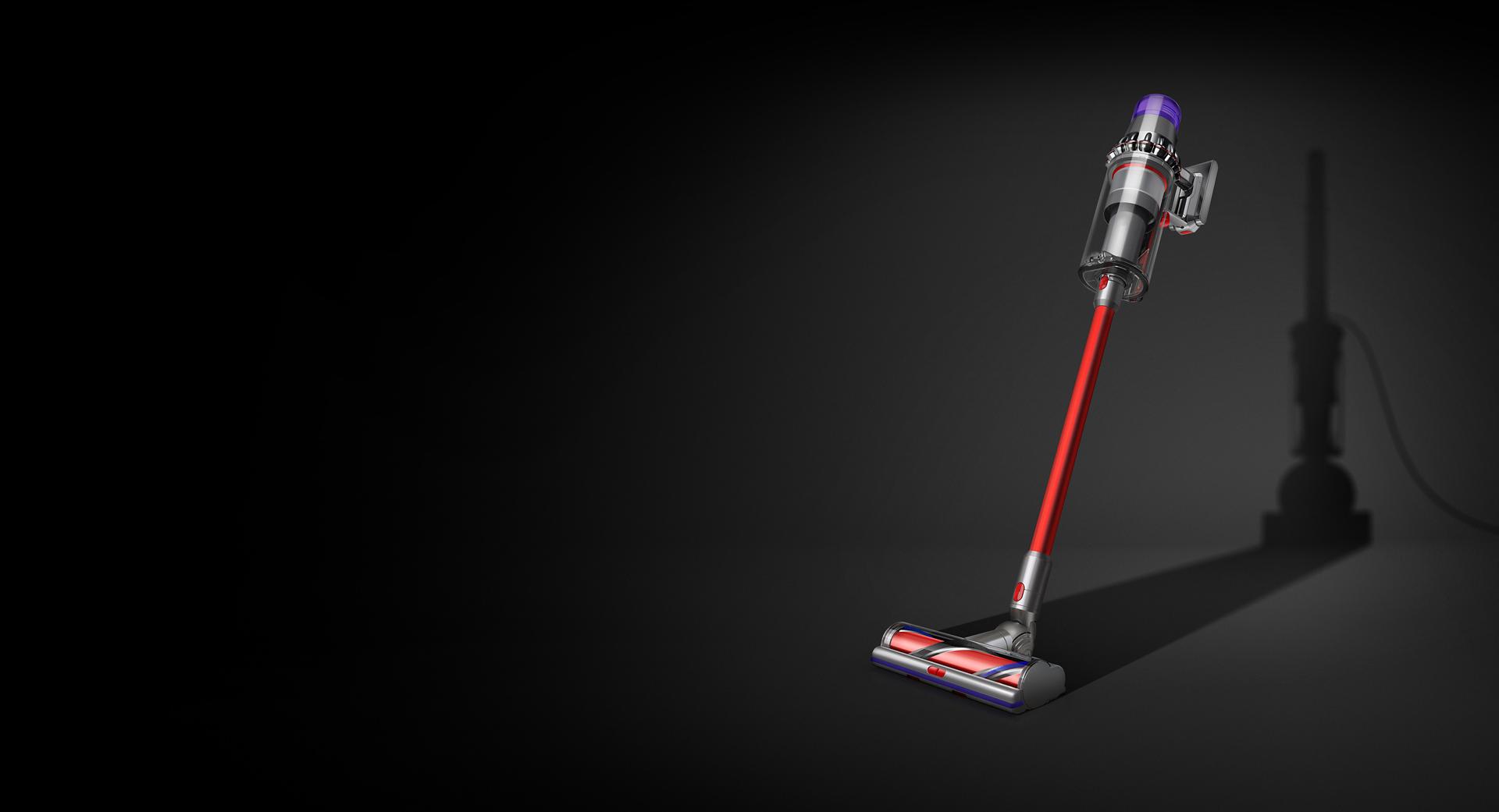 A Dyson V11 Outsize cordless vacuum with the shadow of a corded cleaner