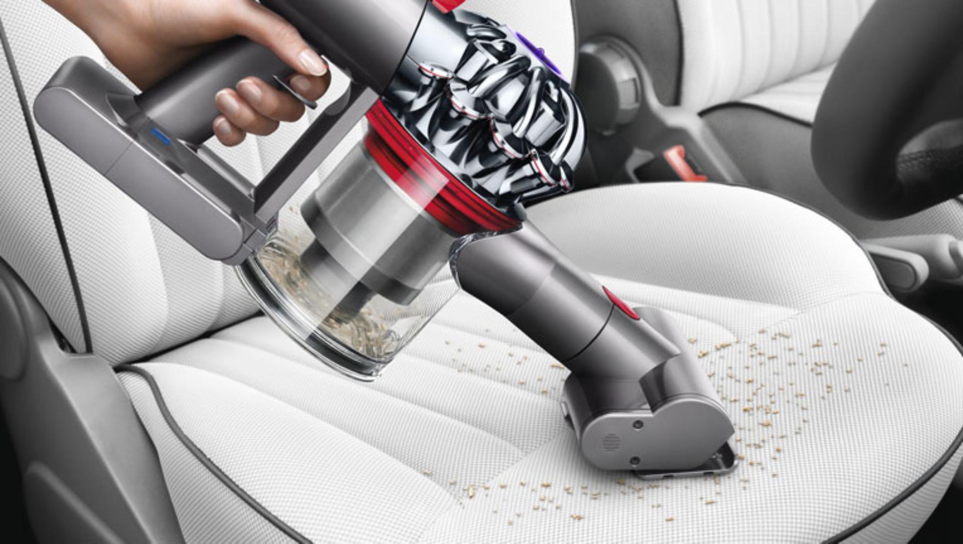 Dyson V8 Slim vacuum in handheld mode cleaning a car seat
