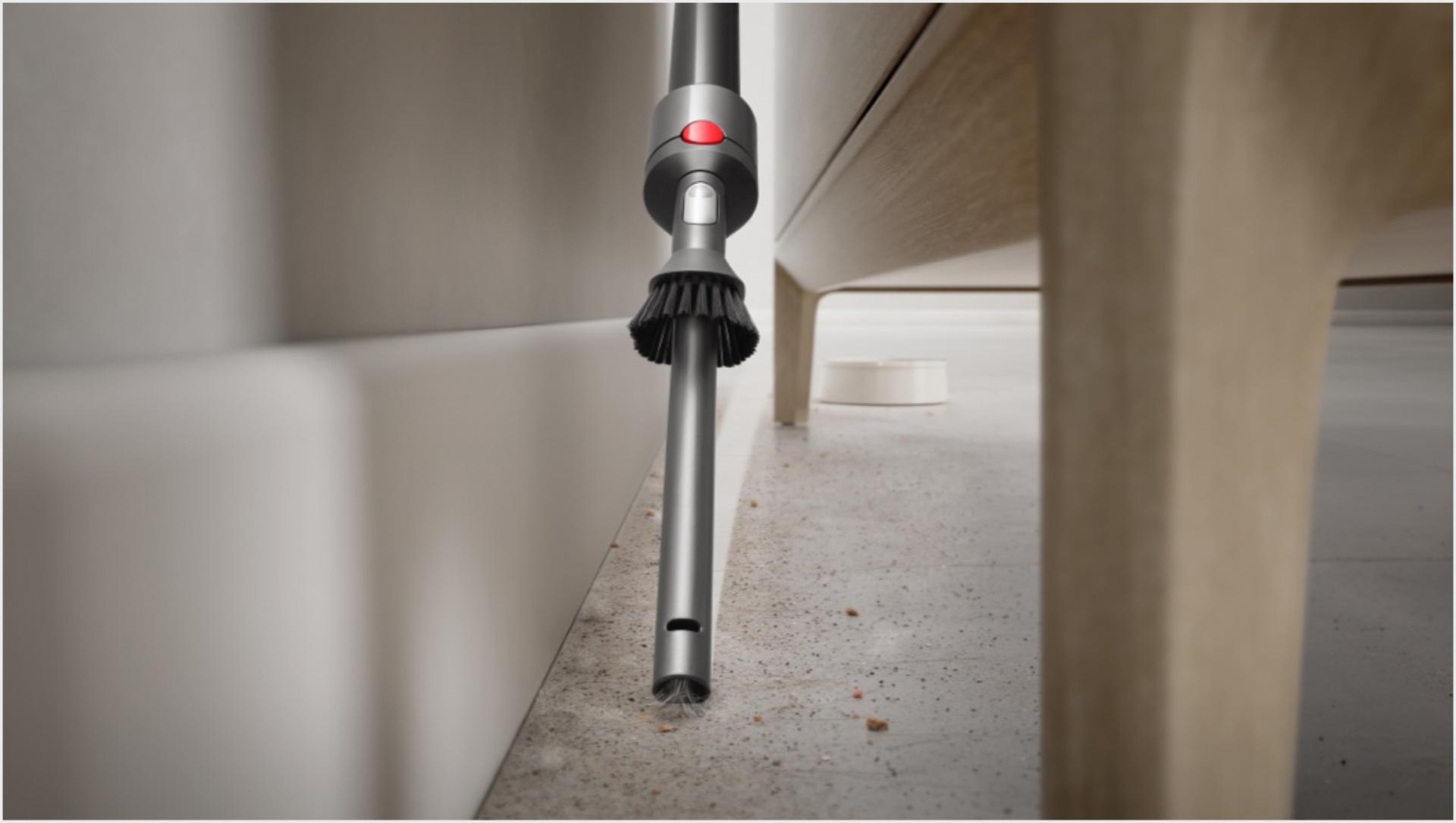 Dyson V7 Advanced with crevice tool attached cleaning behind a piece of furniture