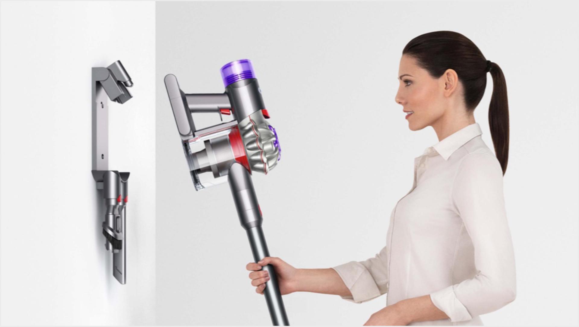 سيدة تقوم بتعليق مكنسة Dyson V8 على وحدة الإرساء الجدارية