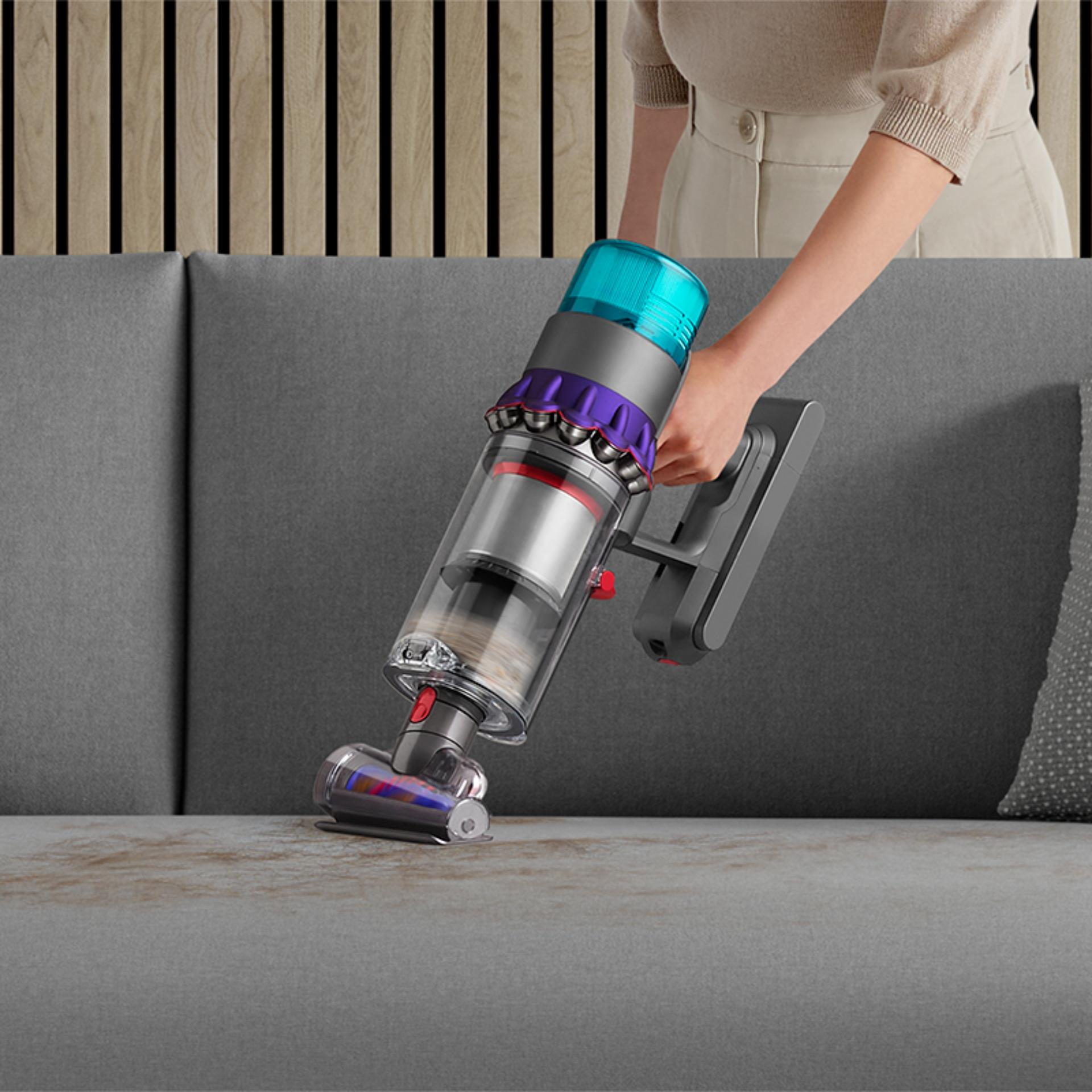 Woman vacuuming pet hair from a sofa, with the Dyson Hair screw tool.