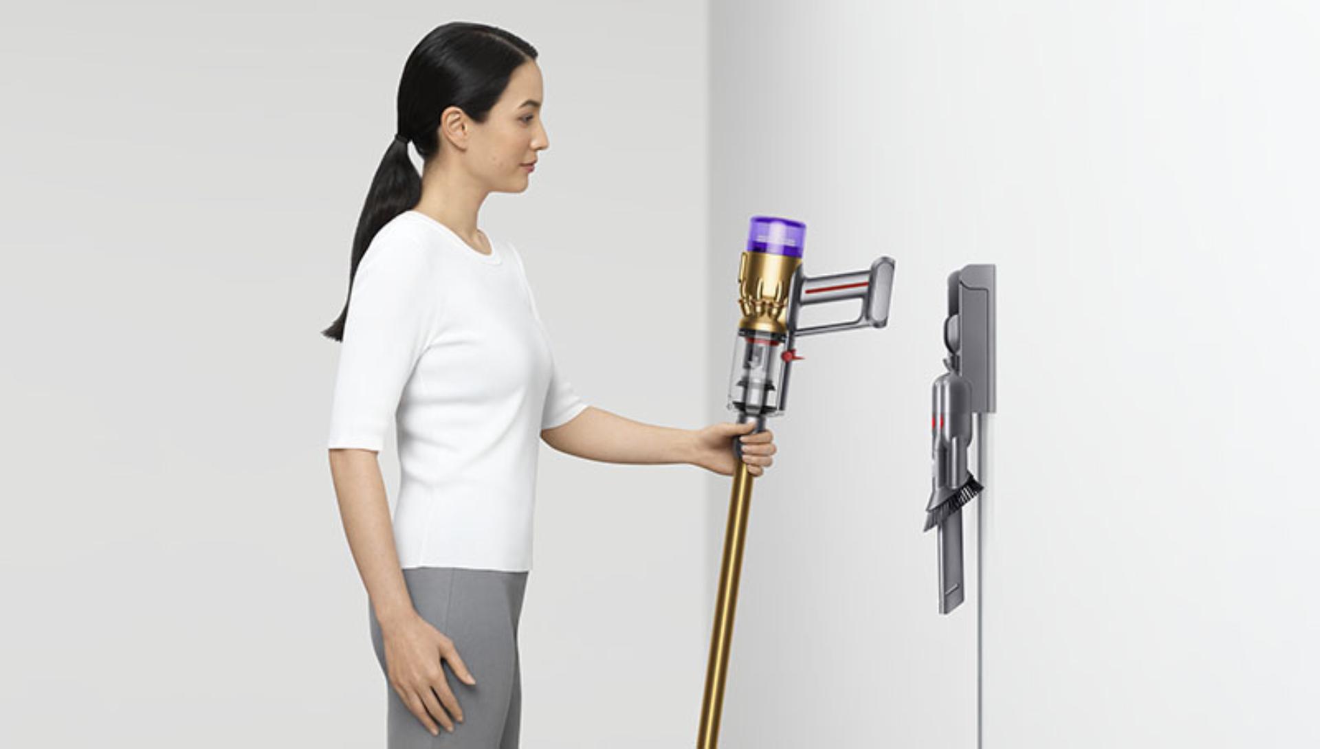 Woman putting a Dyson Micro 1.5kg vacuum into a wall dock