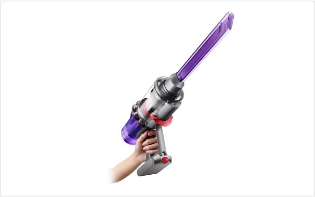 صورة لسيدة تُنظِّف الأماكن العالية وتستخدم المكنسة في الوضعية المحمولة باليد.