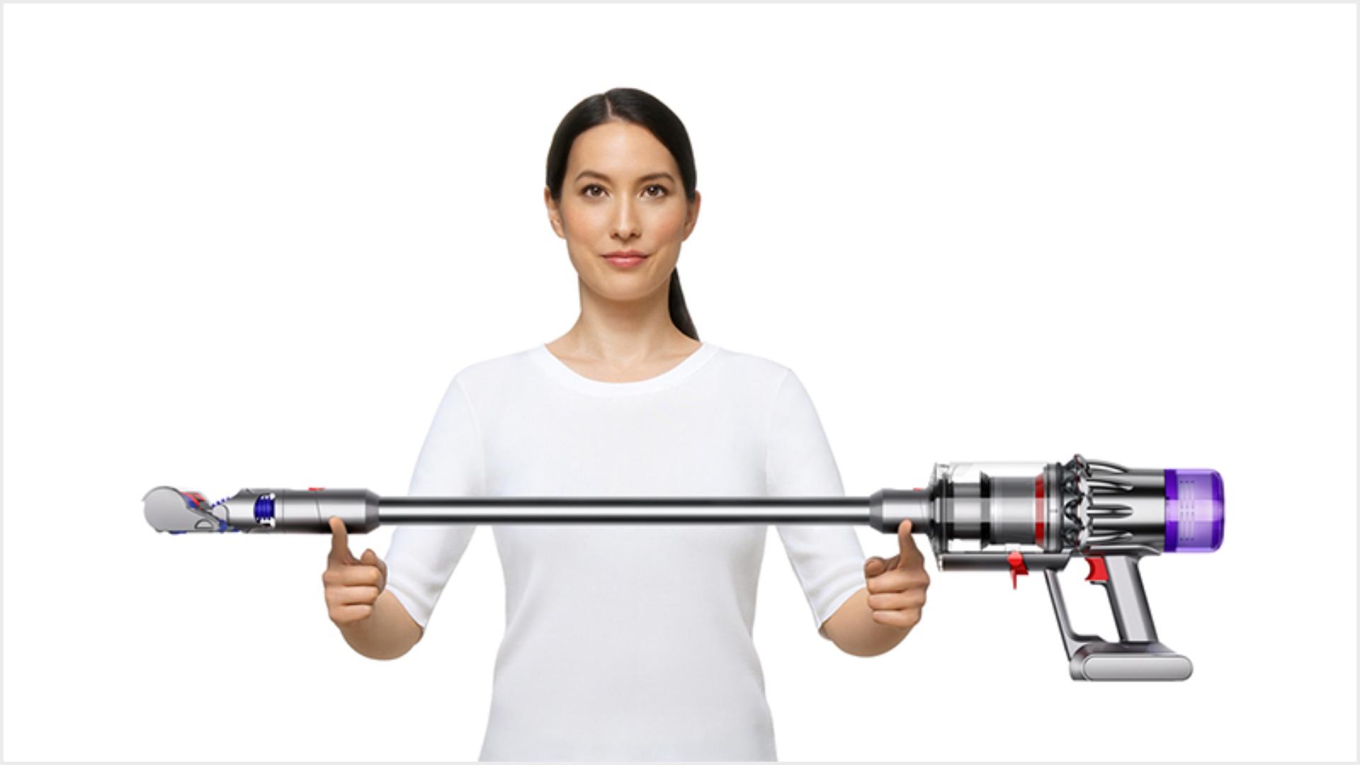 ผู้หญิงขณะกำลังยกเครื่องดูดฝุ่น Dyson Digital Slim ขึ้นมา