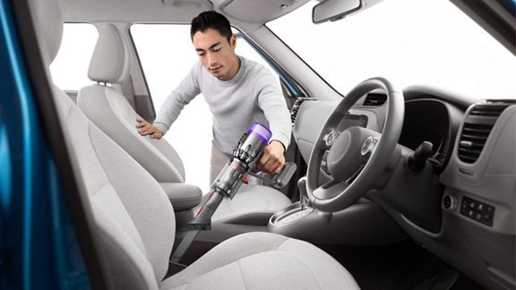 ハンディクリーナーで車の中を掃除する様子