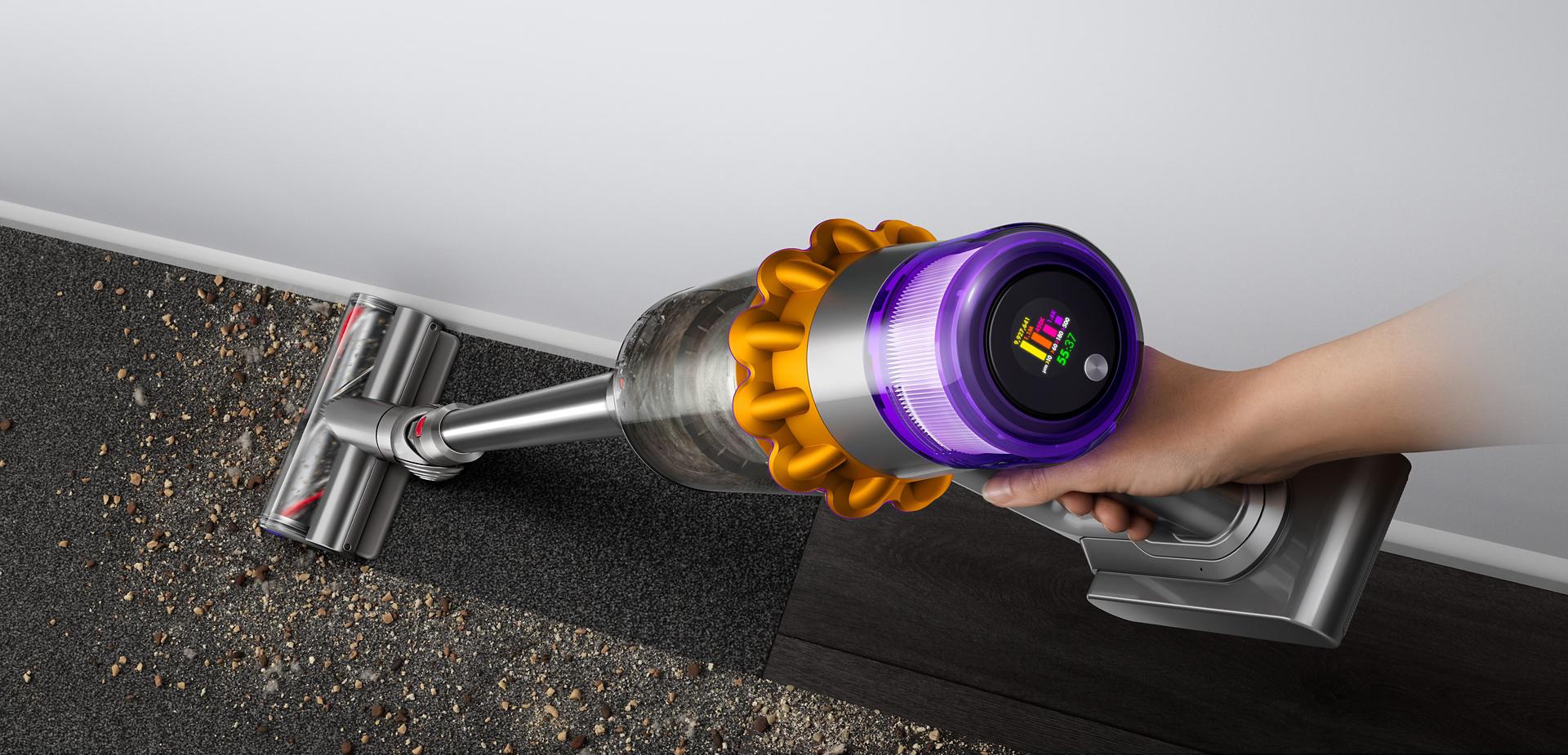 Dyson V15 Detect vacuum cleaning debris from a hard floor next to a wall