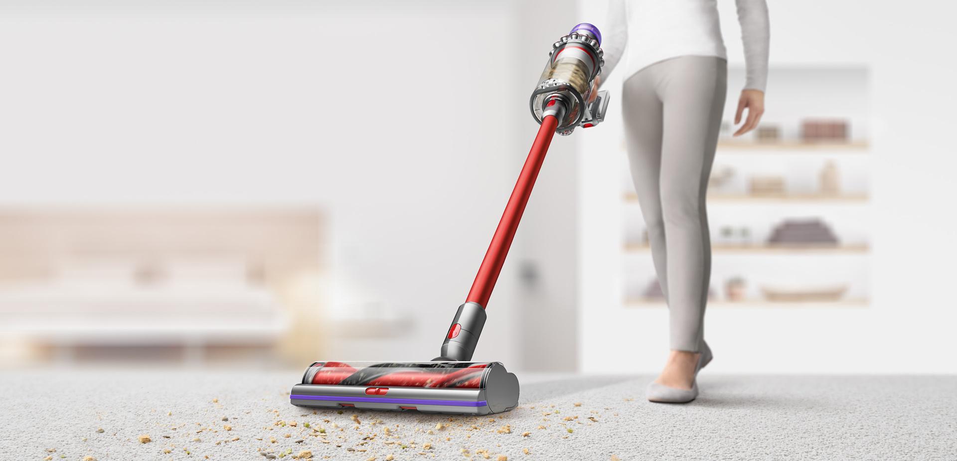 Woman using Dyson Outsize vacuum to clean debris from carpet