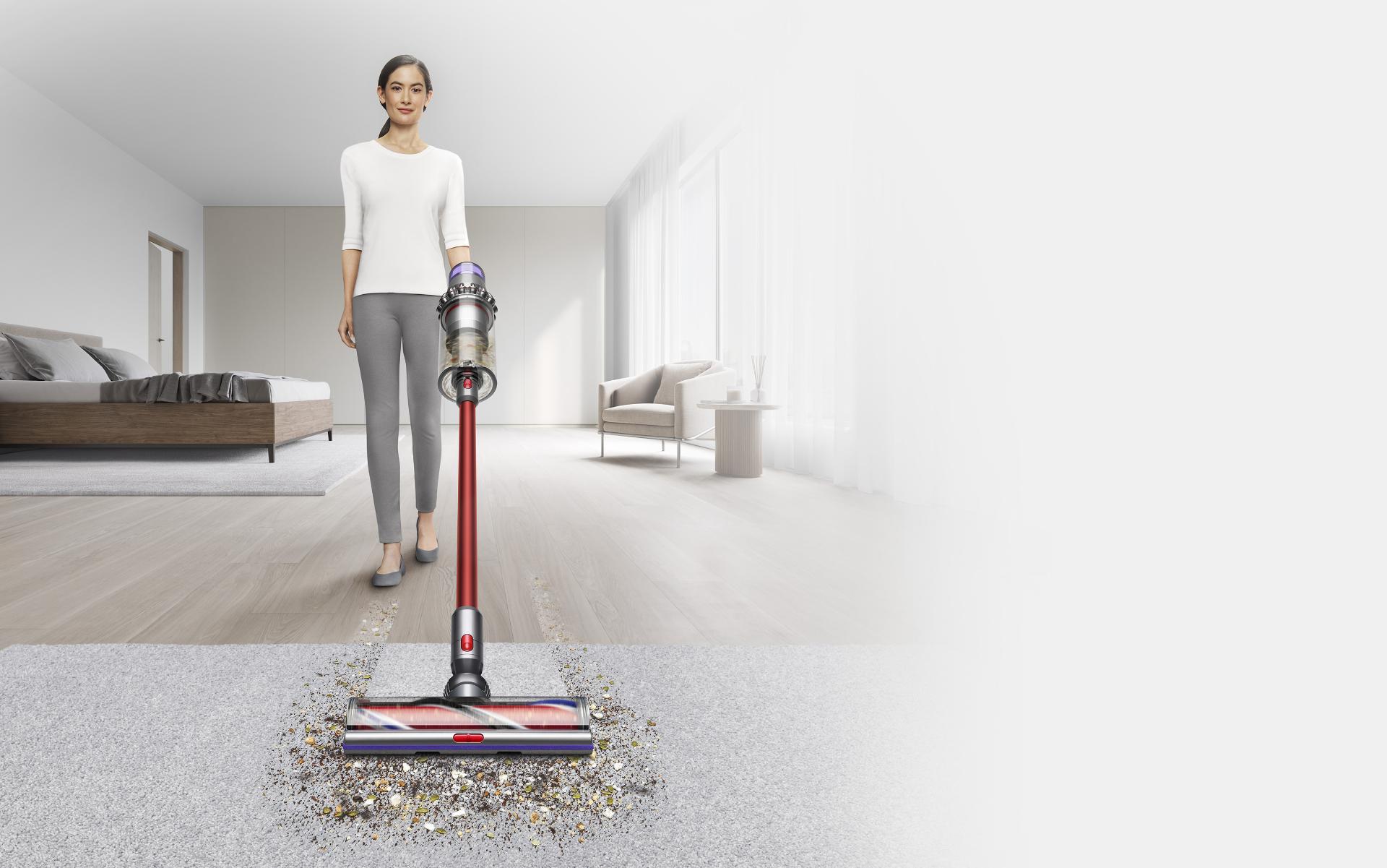 Woman pushing Dyson Outsize vacuum from hard floor to carpet