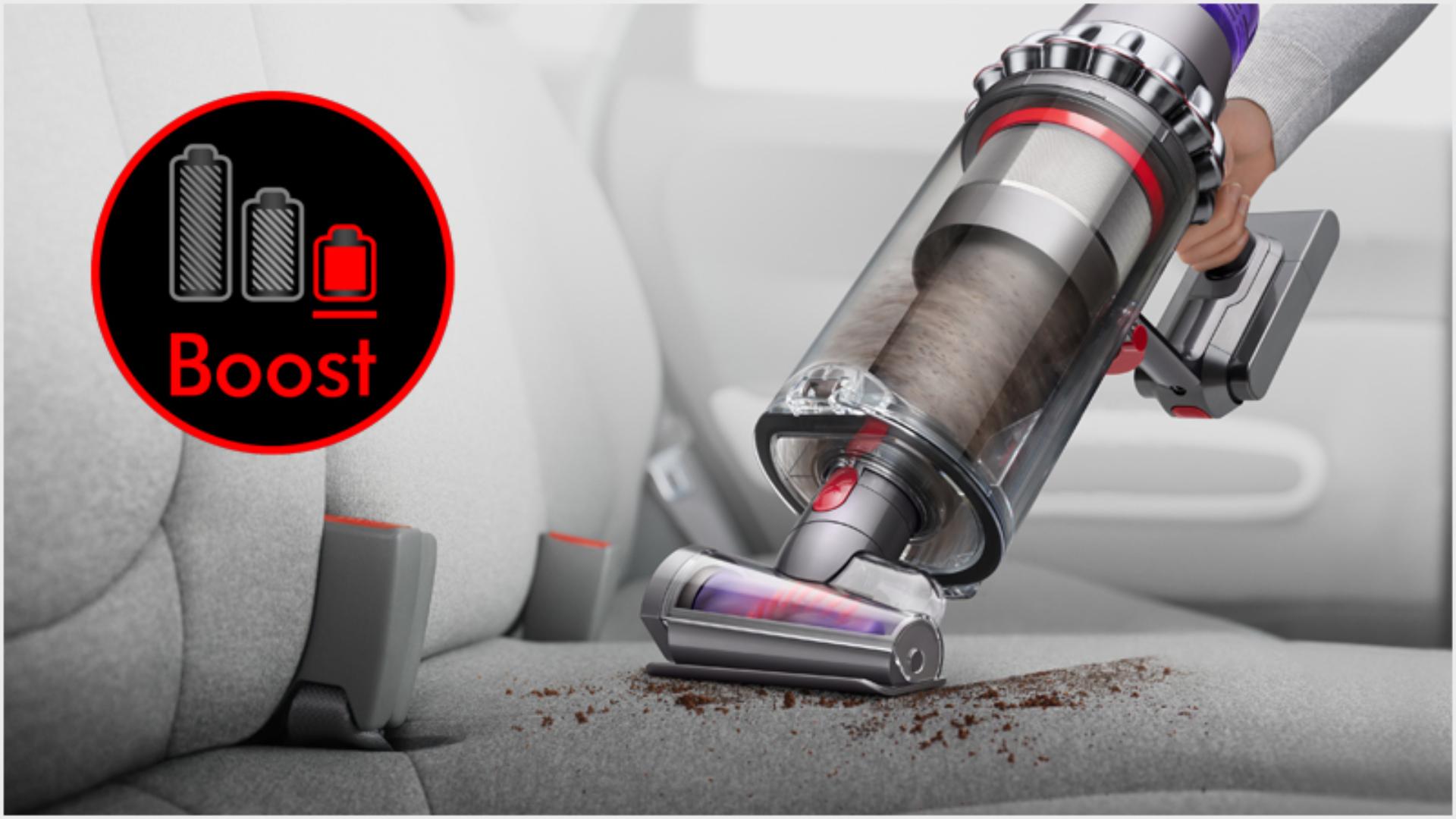 Dyson Outsize vacuum in handheld mode with Hair screw tool, cleaning a car interior.