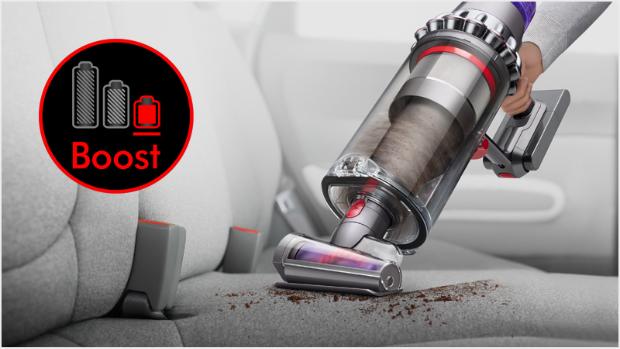 Dyson Outsize vacuum in handheld mode with Hair screw tool, cleaning a car interior.
