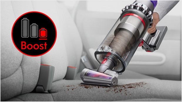 Dyson Outsize vacuum in handheld mode with Hair screw tool, cleaning a car interior.