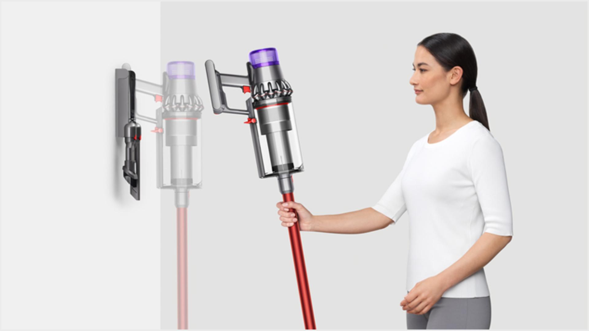 Woman placing Dyson vacuum into the wall dock