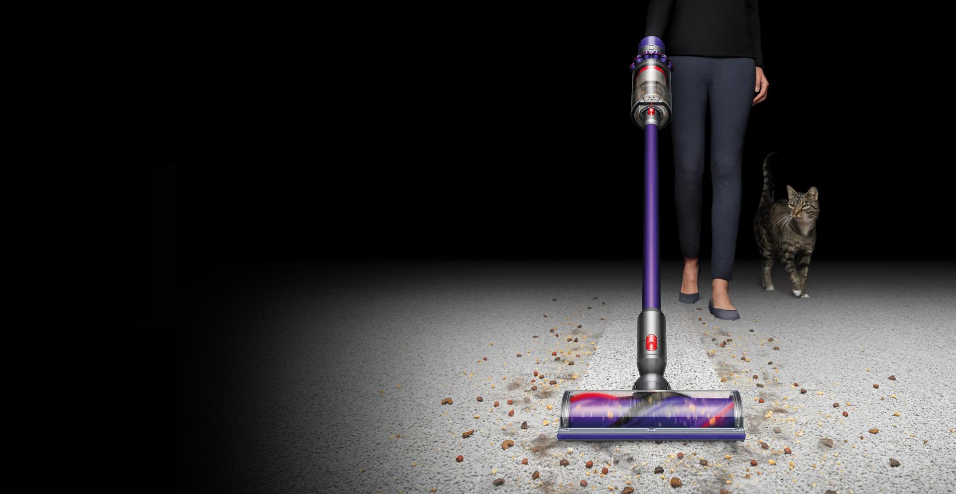 Woman collects dirt using Dyson Cyclone V10 vacuum cleaner.
